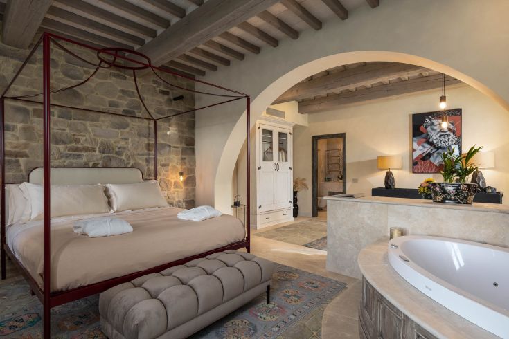 A cozy and understated room featuring a canopy bed, corner bathtub, and simple decor.