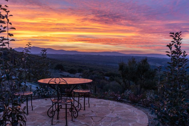 A wrought iron table overlooking a serene sunset. The surrounding nature creates a calm atmosphere.