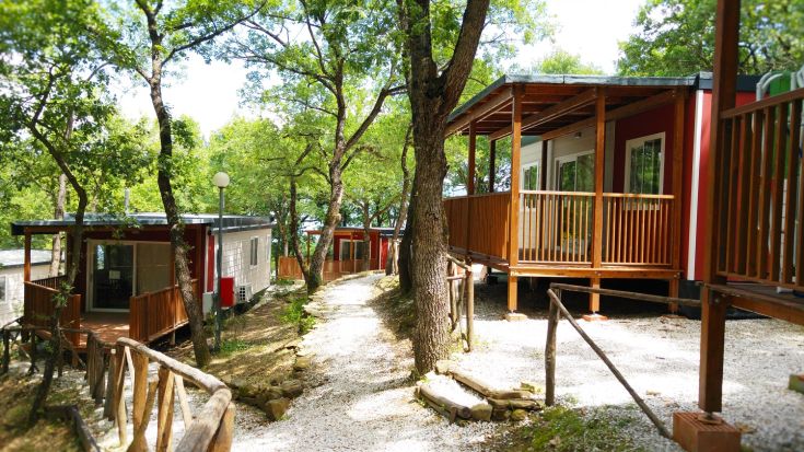 Tourist village surrounded by trees, offering bungalows and paths along the lake.