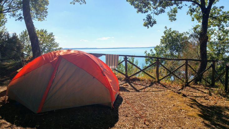 A tent near a lake enjoying a sunny day.