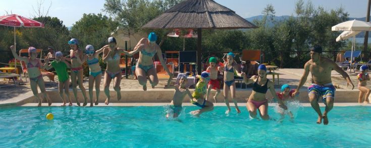 A group of young people jumps into a swimming pool, enjoying the sun and the company of friends.