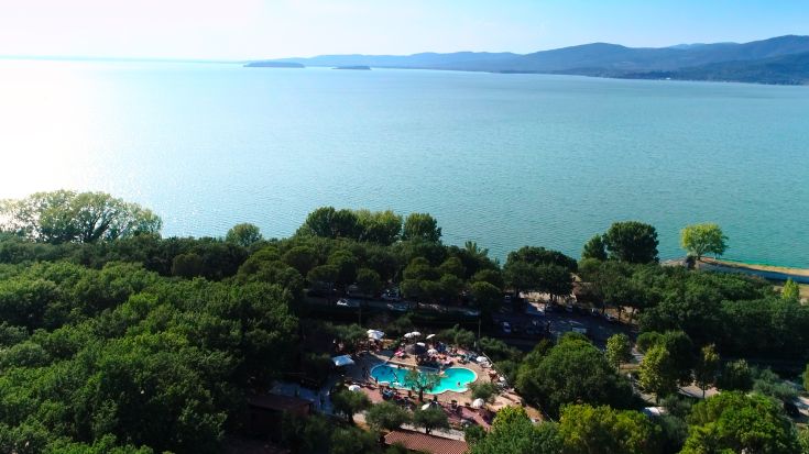 Scene of Camping Village Cerquestra, surrounded by greenery near Lake Trasimeno.