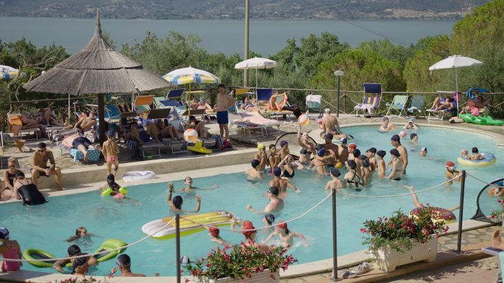 A peaceful summer day at the pool, with families and friends enjoying time together.