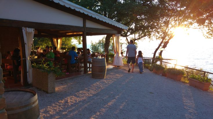 Calm atmosphere at sunset, with outdoor tables by the lake and a serene panorama.