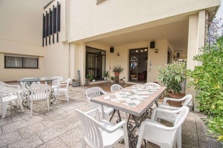 Zona esterna all'hotel con tavoli e sedie, perfetta per passare del tempo all'aperto e sorseggiare una bevanda.