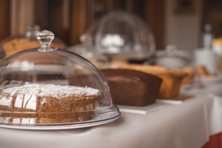 Un assortimento di dolci artigianali esposti sotto campane di vetro presso un negozio di dolciumi.