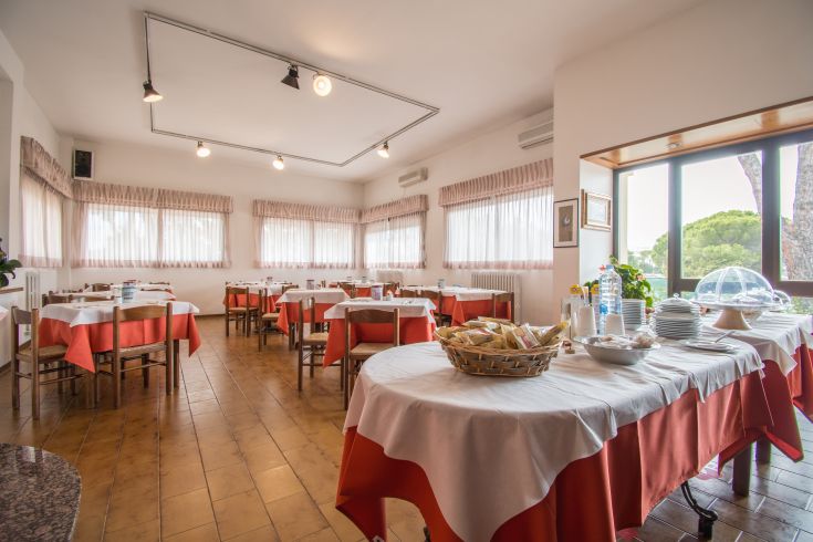 Un ristorante luminoso con tavoli ben apparecchiati e panorama verdeggianti all'esterno.