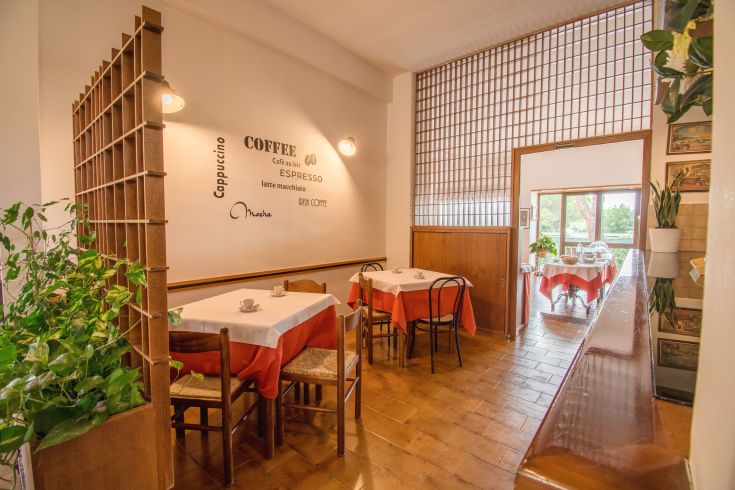 Ristorante semplice con tavoli disposti in modo ordinato e decorazioni sobrie, ideale per un momento di relax.