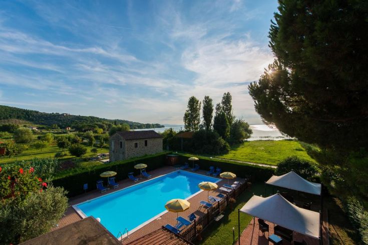 Vue sur le lac Trasimène, avec piscine extérieure et espaces verts pour les clients.
