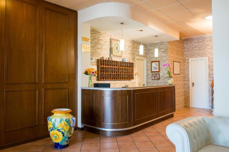 La réception de l'Hôtel Torricella présente un style simple et des meubles fonctionnels, décorée de plantes et de fleurs.