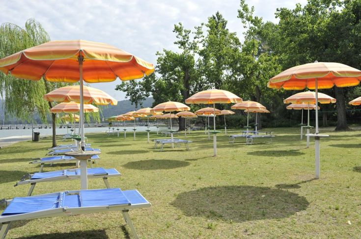 Zone avec des chaises longues et des parasols près du lac Trasimeno, idéale pour un moment de détente.