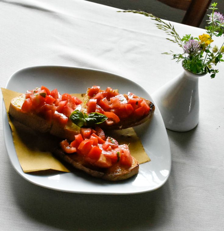 Bruschetta garnie de tomates fraîches et de basilic sur une assiette simple et épurée.