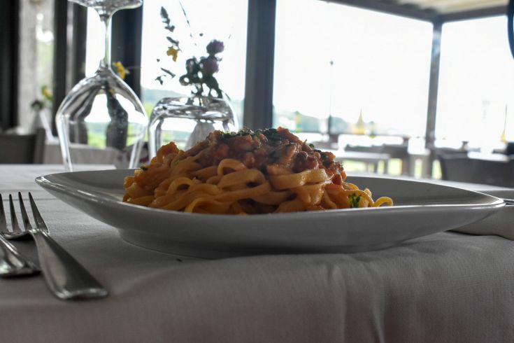 Une assiette de pâtes servie dans un restaurant raffiné avec vue sur le lac, ornée de simples décorations florales.