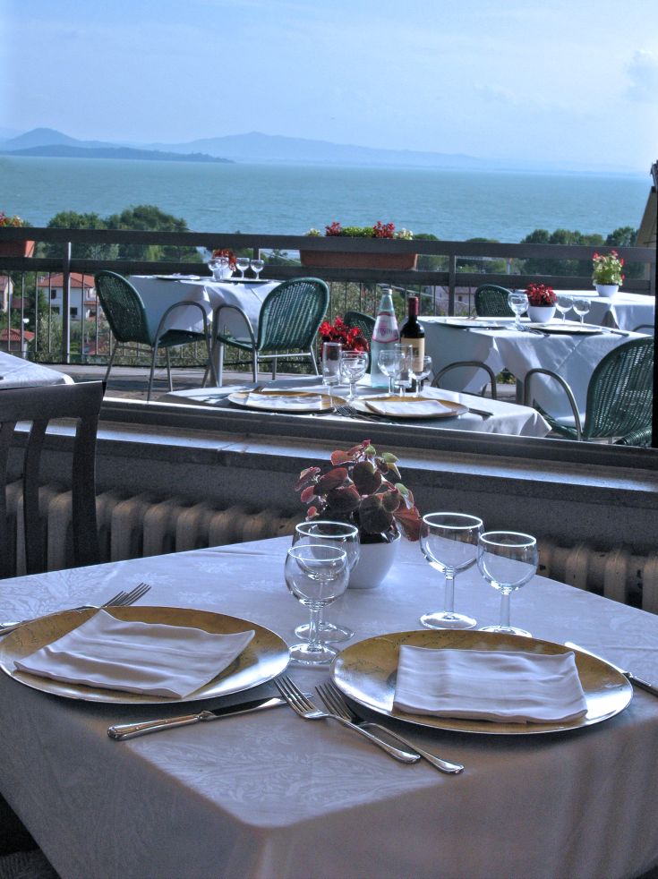 Restaurant donnant sur le lac Trasimeno, avec des tables simplement dressées.