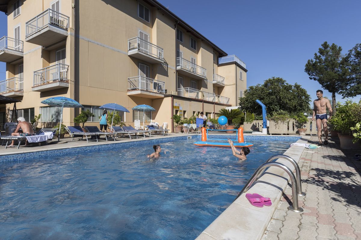 Una piscina accogliente circondata da lettini e ombrelloni, perfetta per il relax nella stagione estiva.