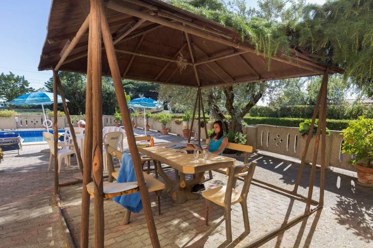 An outdoor relaxation area featuring a table and chairs, with a pool in the background, perfect for leisure.