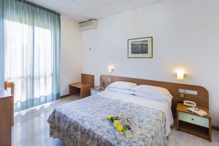 Simple room with a double bed and functional furnishings, providing essential comforts for a pleasant stay.