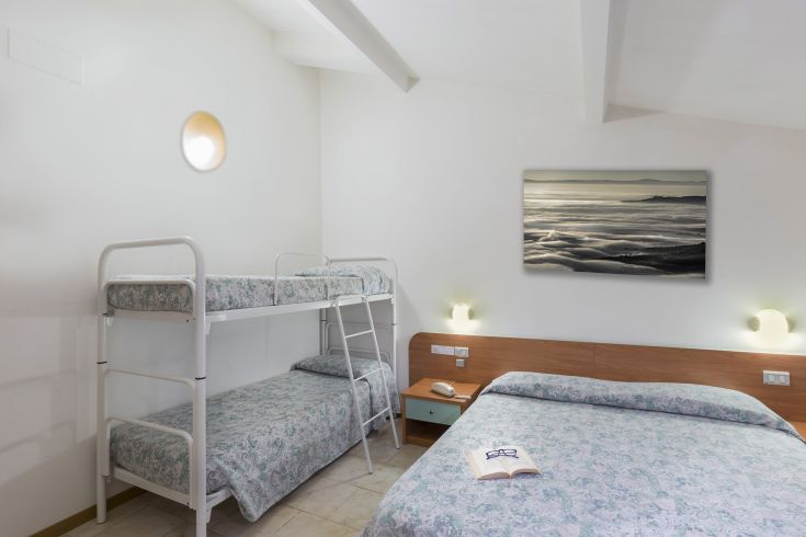 Spacious hotel room with a double bed and bunk beds, well-lit and cozy.