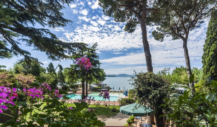 Panoramic view of Hotel Kursaal by Lake Trasimeno, surrounded by flowers and featuring a swimming pool.