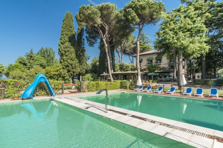A pool surrounded by plants, perfect for relaxing with sun loungers and a slide for children.
