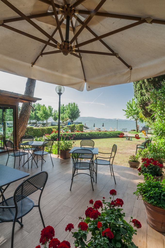 A cozy terrace overlooking Lake Trasimeno, adorned with red flowers. Perfect for moments of relaxation.