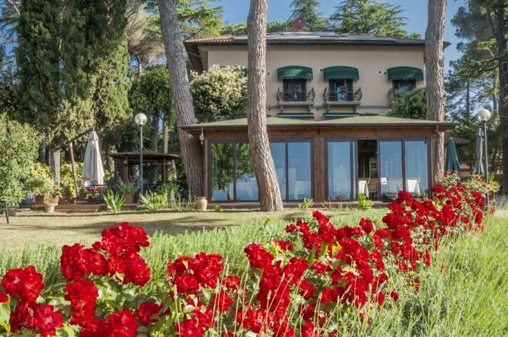 Villa with a green garden by Lake Trasimeno, surrounded by trees in a peaceful atmosphere.