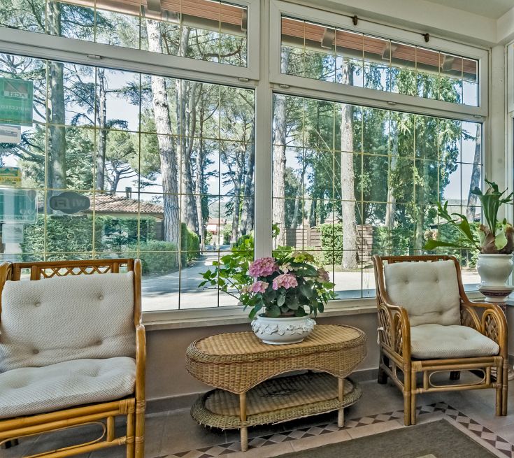 A simple veranda with rattan chairs and plants, overlooking a serene landscape.