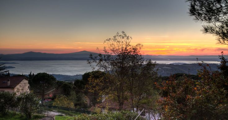 Ein ruhiger Sonnenuntergang über dem See, mit warmen Farben, die sich auf der Wasseroberfläche spiegeln.
