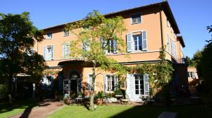 Un hotel accogliente in campagna con stanze arredate in modo semplice, circondato da un giardino tranquillo.