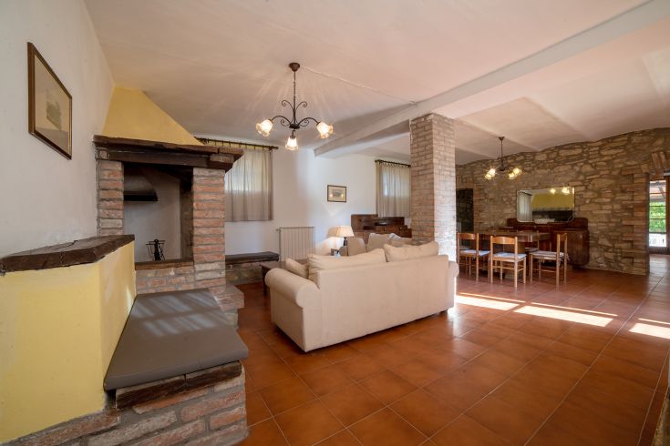 Ampio soggiorno con camino in mattoni, attrezzato con zona pranzo, perfetto per momenti di relax.