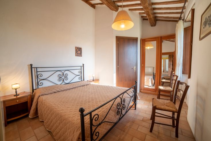 Camera semplice con letti in ferro battuto e mobili in legno. Atmosfera tranquilla e rilassante.