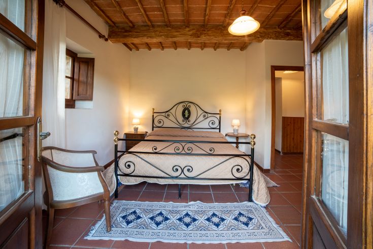 Camera spaziosa con letto matrimoniale, arredamento semplice e panorama sul verde circostante.