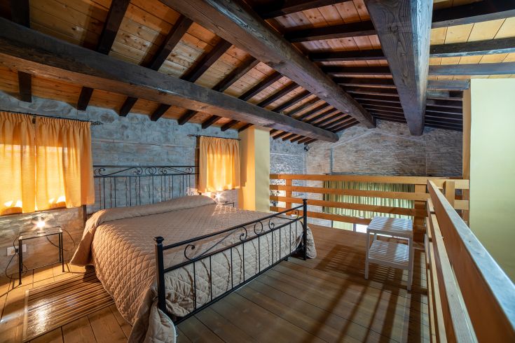 Camera ampia con travi in legno e tonalità calde. Spazio rilassante e confortevole per il riposo.