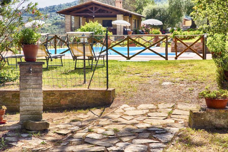 Una scena rilassante con una piscina circondata da un semplice giardino in Umbria.