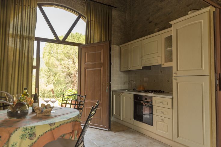 Cucina semplice e accogliente con affaccio su un giardino, ben illuminata e con dettagli in stile rustico.