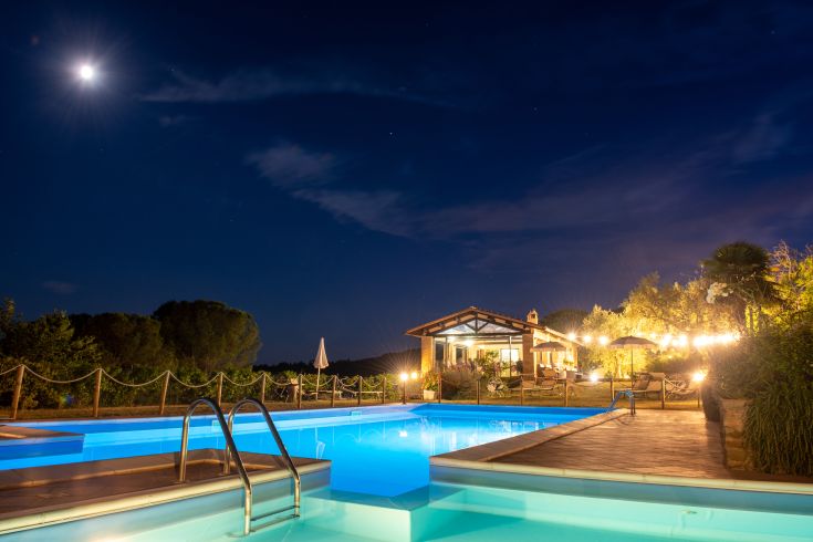 Una serata tranquilla accanto alla piscina, illuminata dalla luna e circondata dalla vegetazione tipica dell'Umbria.