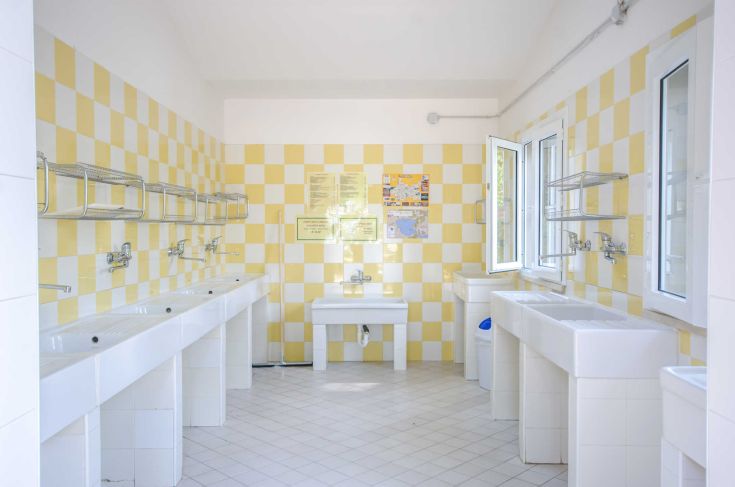 A well-organized bathroom with clean sinks and soft yellow walls, perfect for camping customers.