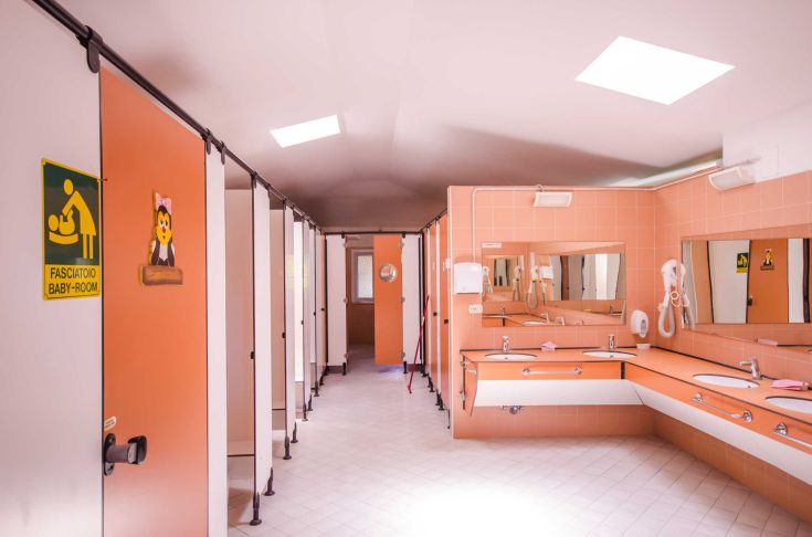 Simple and functional bathrooms with cubicles, mirrors, and changing tables for children.