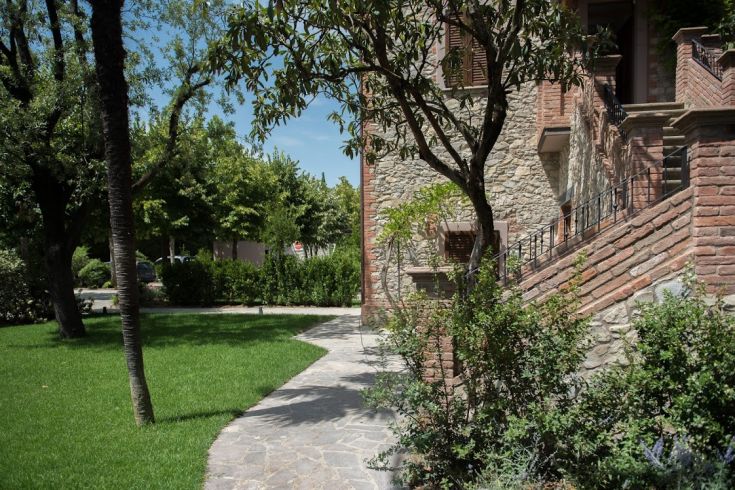 Eine von Bäumen gesäumte Allee führt zum Eingang eines alten Steinpalaus.