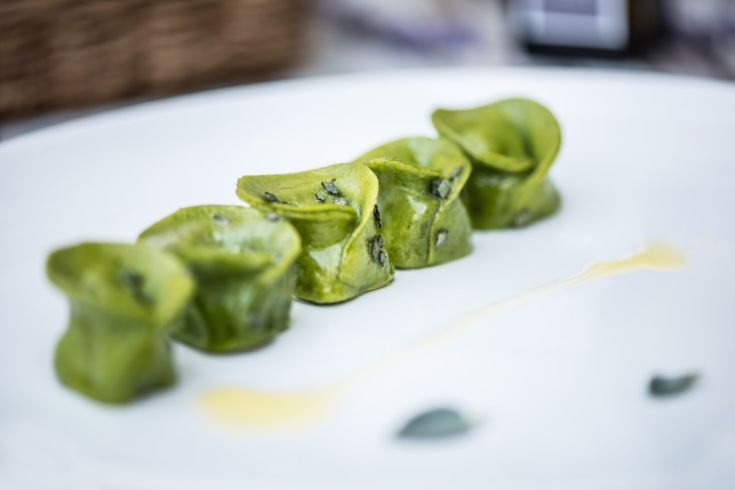 Grüne Ravioli auf einem weißen Teller serviert, betonen die Frische und Kreativität des Gerichts.