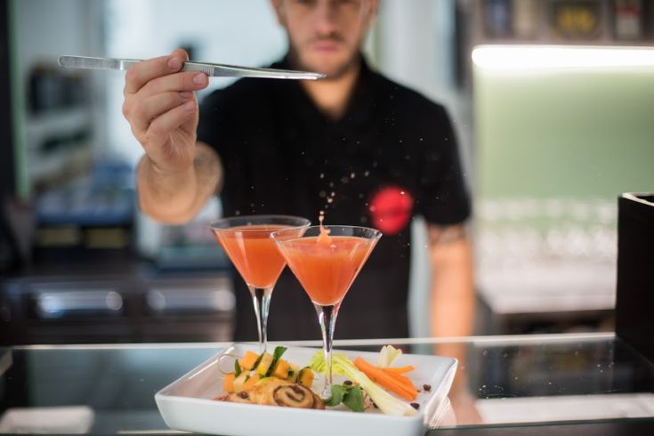 Ein Barkeeper bereitet Cocktails mit frischen Zutaten und bunten Gerichte in einer eleganten Umgebung zu.