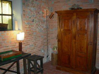 Angolo semplice con un armadio in legno e pareti in mattoni, creando un'atmosfera calda e familiare.