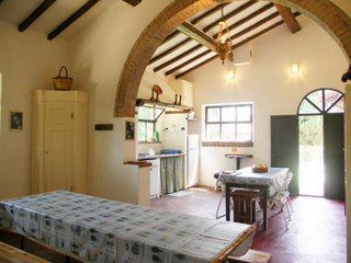 Scena di una cucina rustica all'interno di un agriturismo, con tavoli in legno e decorazioni sobrie.