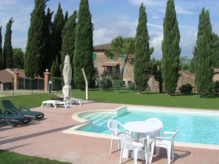 Un rifugio tranquillo con piscina immersa nel verde, circondato da alberi e un edificio rustico nelle vicinanze.