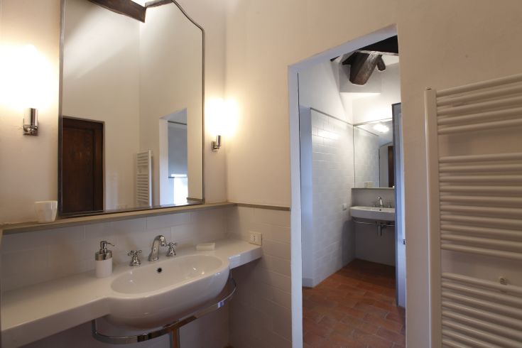 Un bagno moderno e ben illuminato, dotato di uno specchio e di un lavabo semplice.