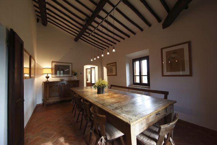 Accogliente sala da pranzo con tavolo in legno e soffitto con travi a vista.