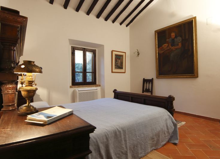 Camera semplice con pareti bianche e qualche decorazione. Una lampada di design e una finestra che porta luce naturale.