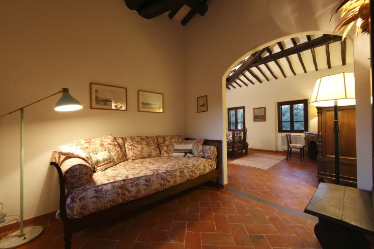 Un soggiorno informale con un divano e una lampada, elementi rustici e un'illuminazione calda.