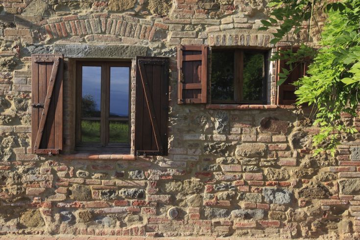 Finestra in legno scuro su un muro di pietra, con elementi rustici che richiamano il passato.