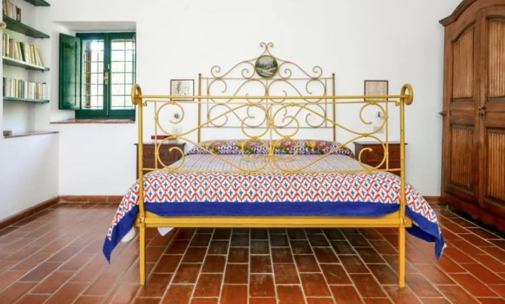 Camera semplice con letto in ferro battuto, decorata con tonalità vivaci e affaccio su una zona tranquilla.